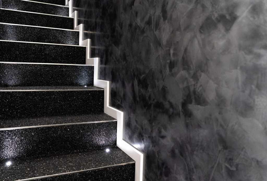 schwarze Treppe mit weißen Leisten neben einer schwarz-weißen Wand